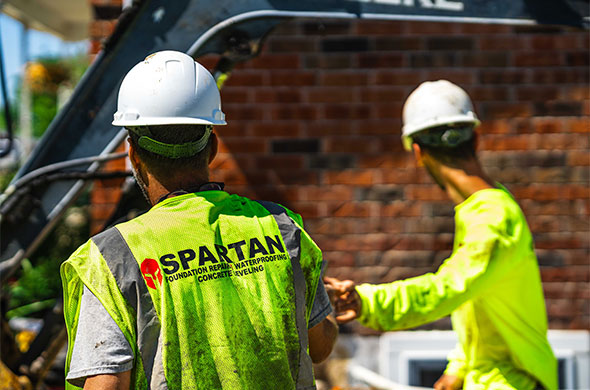 Two men with hard hats and high-vis vests on a construction job site