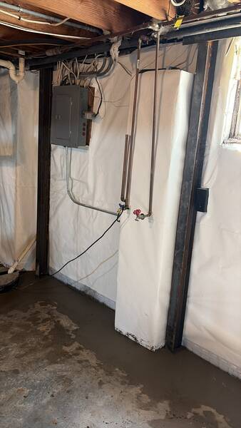 After basement waterproofing and foundation stabilization by Spartan Ram Jack in Roeland Park, KS, showing a clean white wall vapor barrier, steel wall support beams, and a protected basement foundation wall.