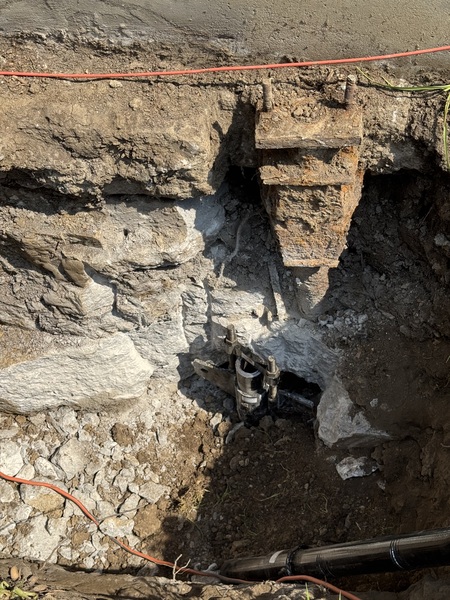 Installed helical pier and foundation bracket beneath a home in Columbia, MO, showing excavation through rocky soil conditions during foundation stabilization by Spartan Ram Jack.