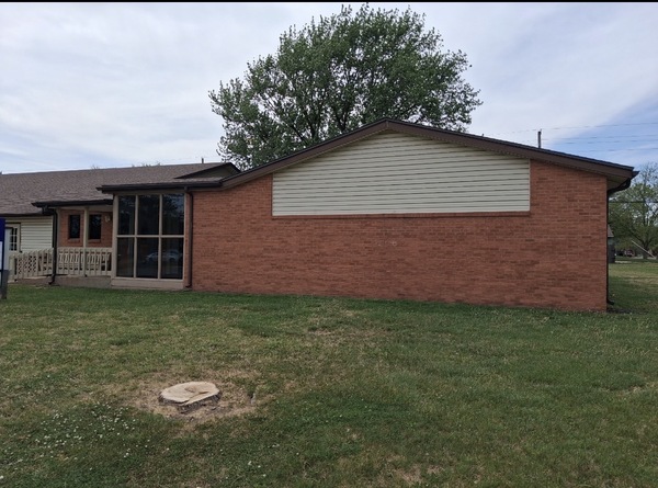 Exterior view of a church in McPherson, KS prior to foundation repair, showing the brick building and area where Spartan Ram Jack of Wichita installed helical piers to stabilize the settling foundation.