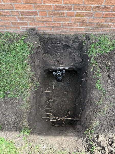 Helical pier installation beneath a brick church in McPherson, KS, showing an excavated foundation footing with a steel pier assembly installed by Spartan Ram Jack of Wichita.