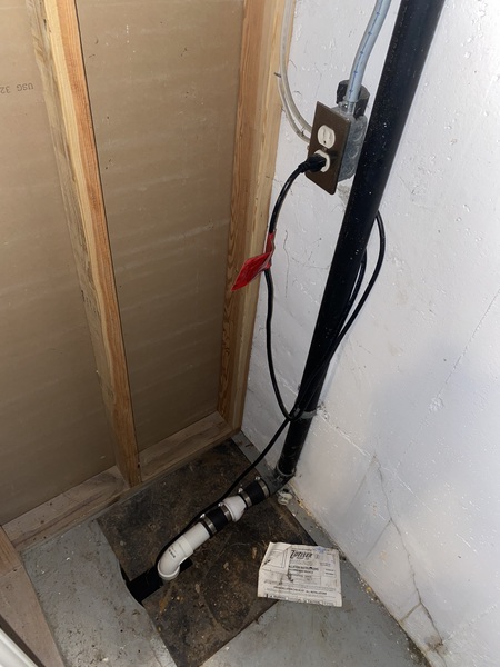 Completed sump pump pit and discharge line installation in a basement in Overland Park, KS, providing improved water management and basement waterproofing protection by Spartan Ram Jack of Kansas City.