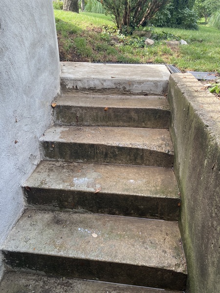 Completed exterior drainage improvement at a basement walkout entrance in Overland Park, KS, showing newly installed channel drain at the top of concrete stairs as part of a waterproofing project by Spartan Ram Jack of Kansas City.