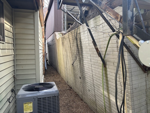 Failing retainment block wall with severe leaning separation between residential structures before earth anchor installation by Spartan Ram Jack.