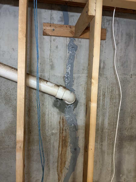 Completed basement wall crack repair in a Springfield, MO home showing a sealed vertical foundation crack and repaired pipe penetration area with epoxy and urethane injection materials applied by Spartan Ram Jack Springfield.