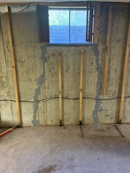 Completed basement wall crack repair beneath a basement window in a Springfield, MO home, showing two foundation cracks sealed with epoxy and urethane injection by Spartan Ram Jack Springfield.