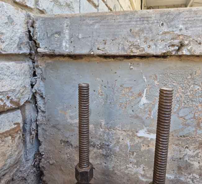 Close-up of a settling foundation corner with visible separation between the concrete porch slab and stone veneer wall, showing signs of foundation movement at a home in Springfield, MO.