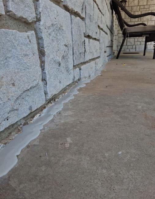 Sealed joint between a stone veneer foundation wall and adjacent concrete patio after foundation repair work, helping protect against moisture intrusion at a home in Springfield, MO.