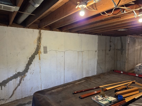 Vertical foundation crack with rust staining running down a basement wall in Excelsior Springs, MO, showing signs of past water intrusion.