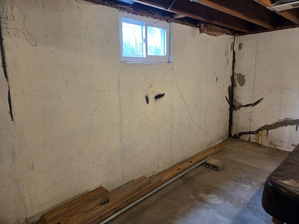 Horizontal and stair-step foundation wall cracks visible in an unfinished basement in Excelsior Springs, MO, indicating foundation settlement and structural movement.