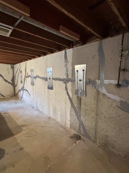 Interior steel wall plates installed along a cracked basement wall as part of a concrete earth anchor system in Excelsior Springs, MO.