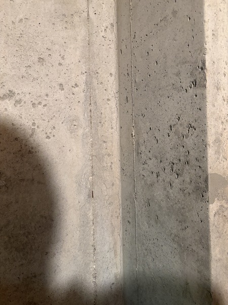 Vertical foundation crack repaired with sealant on an interior poured concrete basement wall.