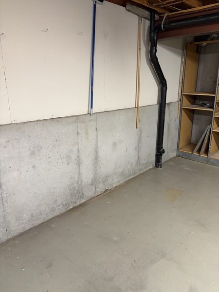 Basement foundation wall with visible moisture staining and a repaired vertical crack in a Lee's Summit, MO home.